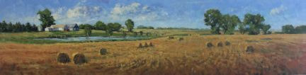 Baled wheat field with farm house and pond in distance.