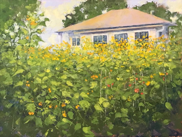 Sunflowers rise up against a small home