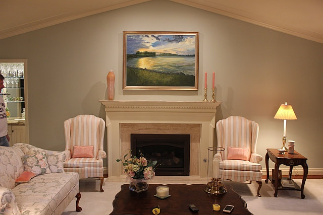 Beautiful home with painting of lake above fireplace.